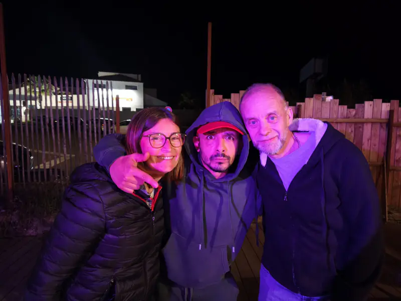Trois membres du club épaule contre épaule sur la terrasse, à la nuit tombée